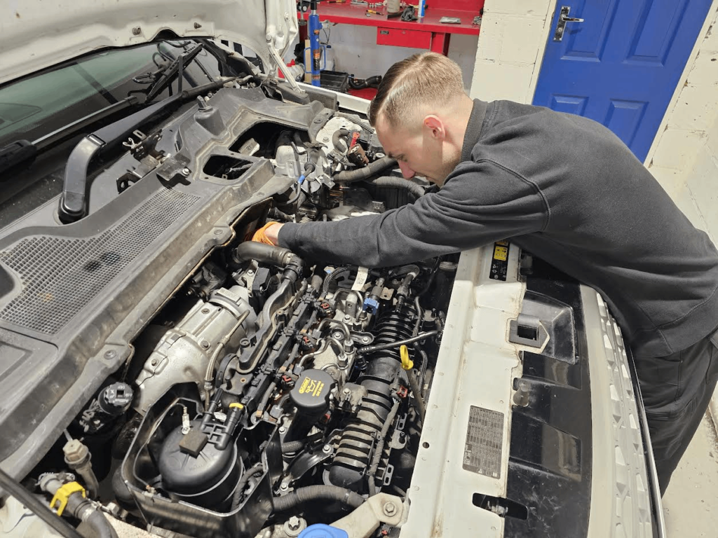 Mechaniker arbeitet bei Motorüberholung eines Land Rover Range Rover Defender